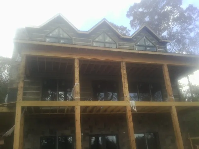 Dormers and porch framing on a large log home under construction — Roof Coating work by our crew in Haven