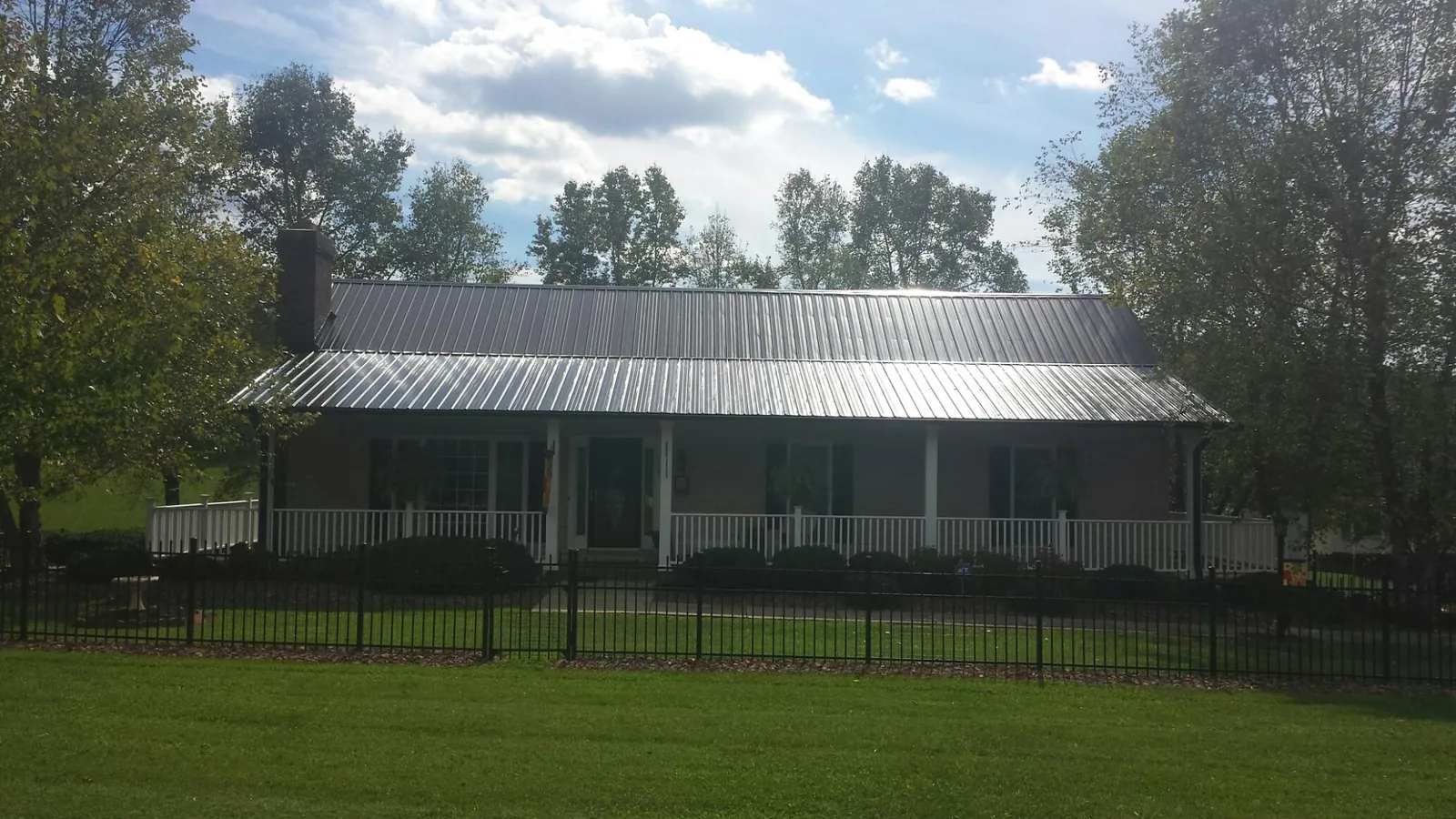 Gray metal roof on a brick ranch with a full width front porch — Gutter Guard Installation work by our crew in Haven