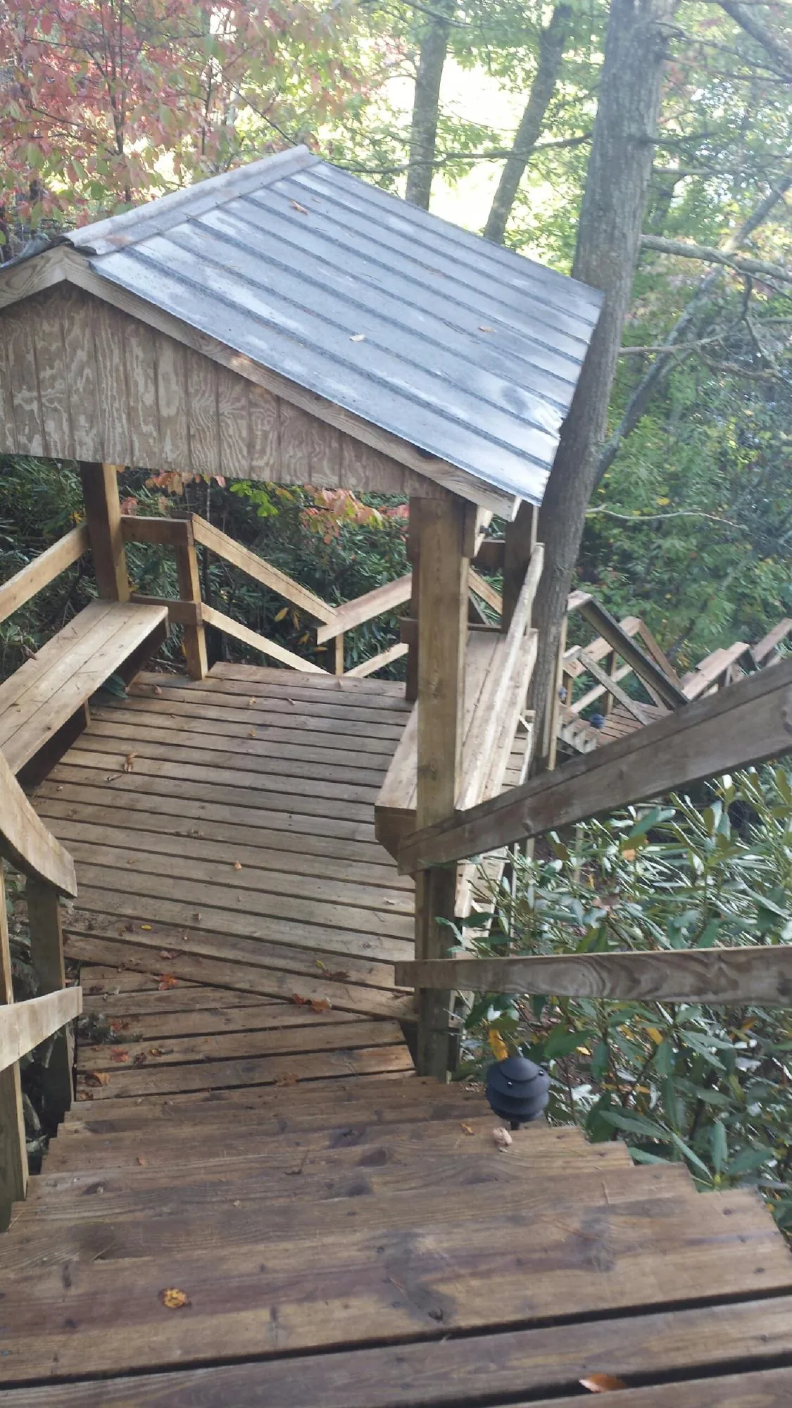 Metal roofed shelter over wooden steps on a wooded walkway — Skylight Repair & Installation work by our crew in Haven