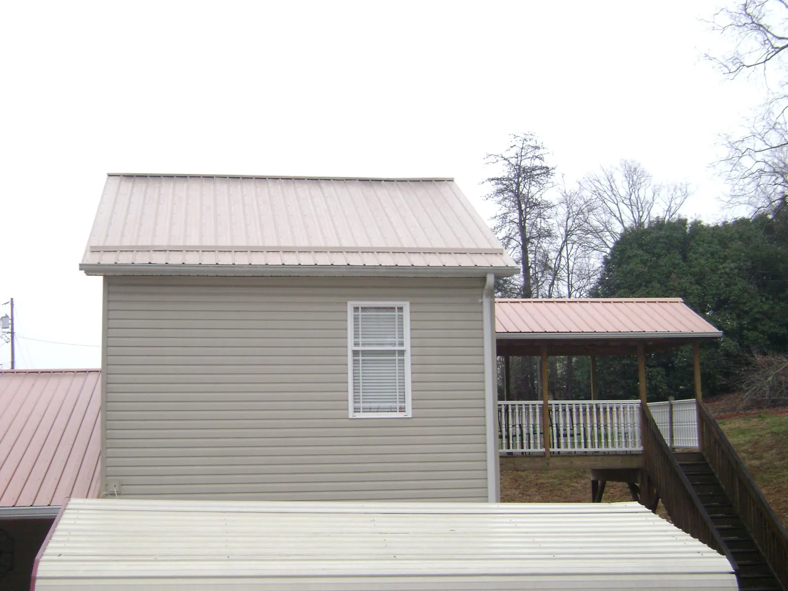 Tan metal roofs on a two story addition and attached porch, from a Roof Replacement job in Haven
